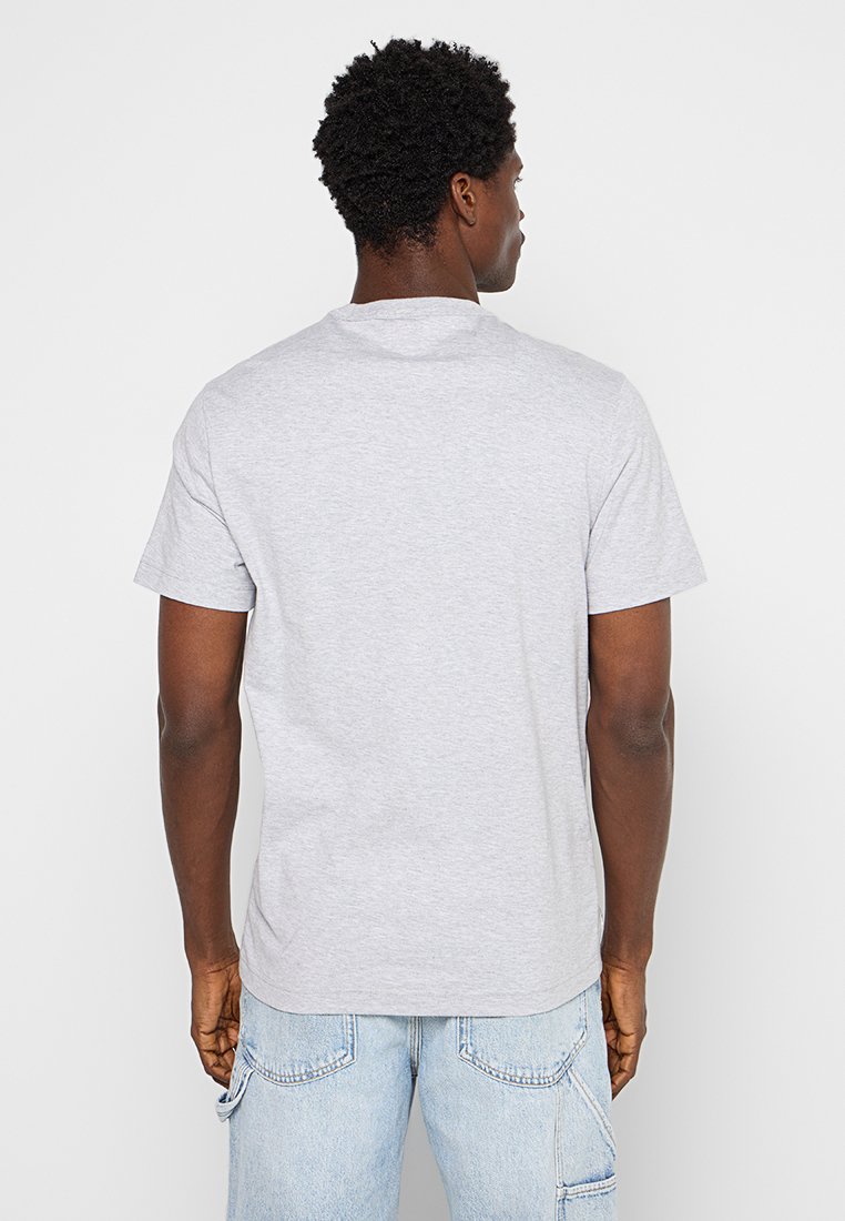 Graues Baumwoll-T-Shirt mit kurzen Ärmeln, Rundhalsausschnitt und lockerer Passform, von hinten gezeigt. Kombiniert mit hellblauen Jeans.