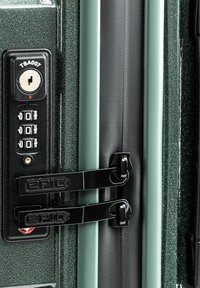 Valigia rigida con un'esterno verde strutturato, dotata di una combinazione di lucchetto, lucchetto TSA e due ganci neri per la sicurezza.