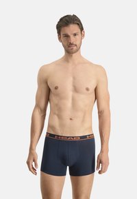 Boxers navy en tissu lisse, avec une ceinture logotypée orange. Les shorts ont une coupe ajustée avec un ourlet droit.