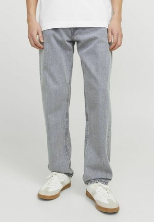 Jeans rectos de color gris claro con costuras visibles, textura ligeramente desgastada y un corte relajado; combinados con zapatillas deportivas blancas.