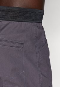 Gray fabric shorts with a textured black elastic waistband. Features include pockets and contrasting blue stitching details.