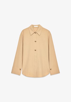 Beež pusa, millel on pikad varrukad, terav krae ja kaks esist nuppu. Sile kangateks ja mugav lõige.