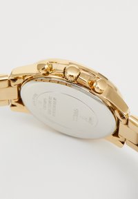 Guld-tone chronograf armbåndsur med et rustfrit stålarmbånd, tre trykknapper og en glat sølvfarvet bagside. Har et elegant design.