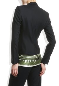 Černý blazer s fitted designem a strukturovanými rameny. Spodní lem obsahuje látku se zeleno-bílým vzorem.