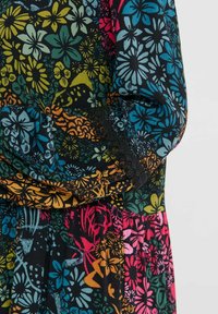 Manche longue de robe et taille avec imprimé floral dense en bleu, jaune, orange, rose et vert sur tissu noir, avec bordure en dentelle au poignet.