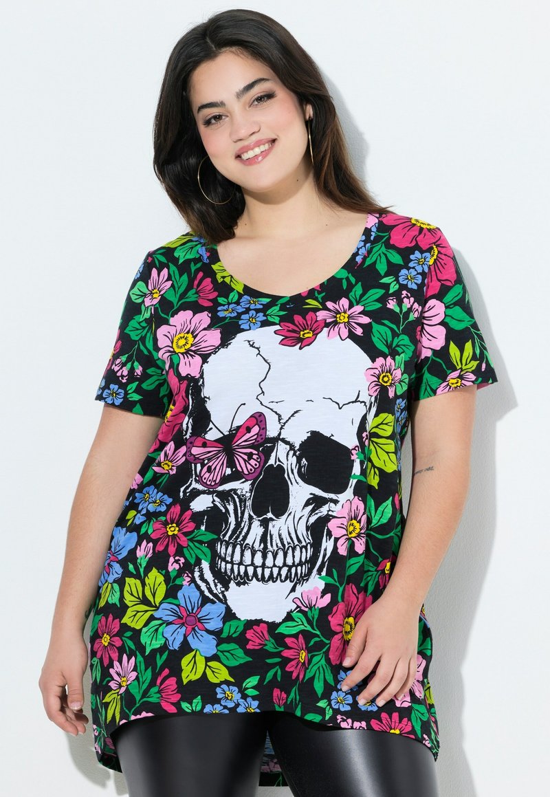 Camiseta negra con estampado floral que presenta un gran gráfico de calavera, acentuado con una mariposa rosa y flores vibrantes en rosa, azul y verde.