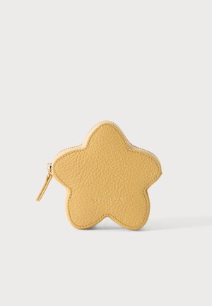 Porte-monnaie jaune en cuir texturé en forme d’étoile, avec une fermeture éclair sur le côté gauche, posé sur un fond clair et uni.
