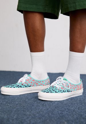 Colorful canvas sneakers with a multi-color leopard print pattern featuring turquoise, pink, and black. White laces and rubber soles.