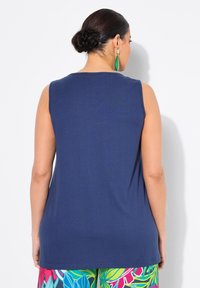 Top senza maniche blu navy con scollatura rotonda, realizzato in un tessuto liscio. Sul retro presenta una vestibilità morbida, abbinato a pantaloni dai colori vivaci e fantasiosi.
