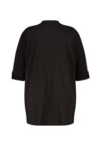 Zwarte oversized T-shirt van zachte stof, met een ronde halslijn en opgerolde mouwen. Eenvoudige, gladde textuur zonder patronen.