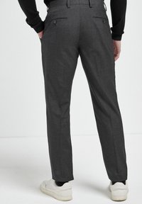 Grau maßgeschneiderte Hose mit feiner Textur, zwei Gesäßtaschen und flachem Vorderdesign, kombiniert mit weißen Sneakers.