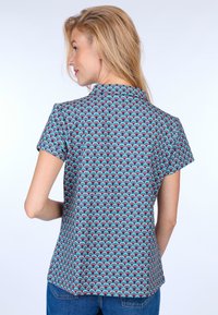 Patterned short-sleeve blouse featuring a wave design in turquoise, pink, and purple against a dark background; relaxed fit and collar detail.