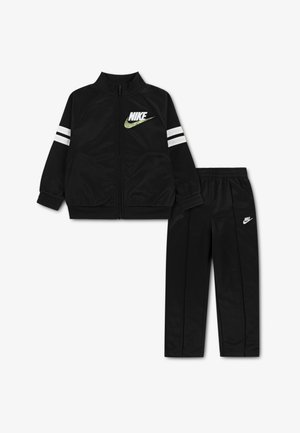 Fekete Nike melegítő, cipzáras felsővel és gumis derekú nadrággal, fehér és zöld csíkos dizájnnal és logó részletekkel.