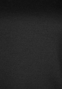 Tissu tricot noir, présentant une texture lisse avec un léger éclat uniforme. Aucune motif ou embellissement distinct visible.