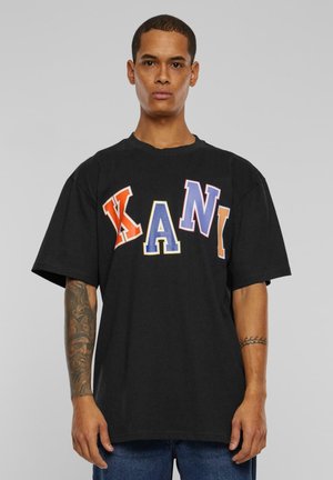 Sort oversized T-shirt med store, multikolorede bogstaver, der staver "KANI." Lavet af bomuld med rund halsudskæring og korte ærmer.