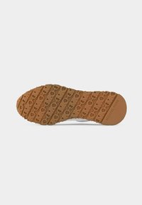 Semelle de chaussure en caoutchouc marron avec un motif répétitif en forme de chaîne et le logo "Michael Kors" près du talon.
