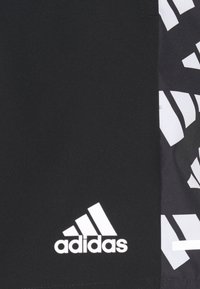 Tela negra con el logotipo blanco de Adidas y un patrón geométrico blanco parcial en el lado derecho.