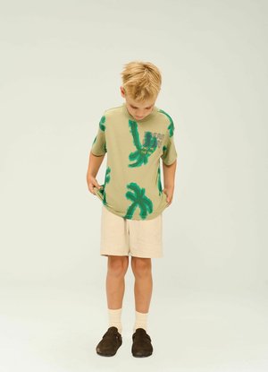 Olivgrön kortärmad skjorta med gröna palmträmönster, texten "FIND ME", i Kombination med ljusbeiga shorts och mörkbruna skor.