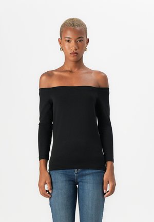 Svart avskåret topp med lange ermer. Laget av mykt stoff, den har en tettsittende design og en jevn tekstur. Kombinert med blå jeans.