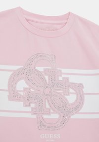 Gai�ši rozā kokvilnas T-krekls ar metāliski spīdīgu logo dizainu, rotāts ar rhinestones un baltām horizontālām svītrām krūšu daļā.