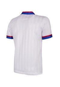 Witte polo met korte mouwen en verticale strepen. Heeft rode en blauwe accenten op de kraag en mouwmanschetten. Gladde stoftextuur.