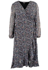 Robe portefeuille à imprimé floral en bleu marine foncé avec manches longues transparentes. Elle présente un décolleté en V profond, un ruban à nouer à la taille et un ourlet à volants.