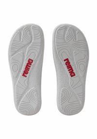 Plantillas de chanclas blancas con patrones texturizados, surcos y un prominente logo rojo "reima" en la plantilla izquierda.
