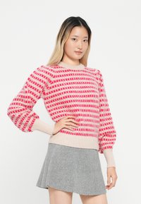 Różowy i beżowy sweter dzianinowy z paskowanym wzorem, z prążkowanymi mankietami i okrągłym dekoltem, połączony z szarością spódnicą.