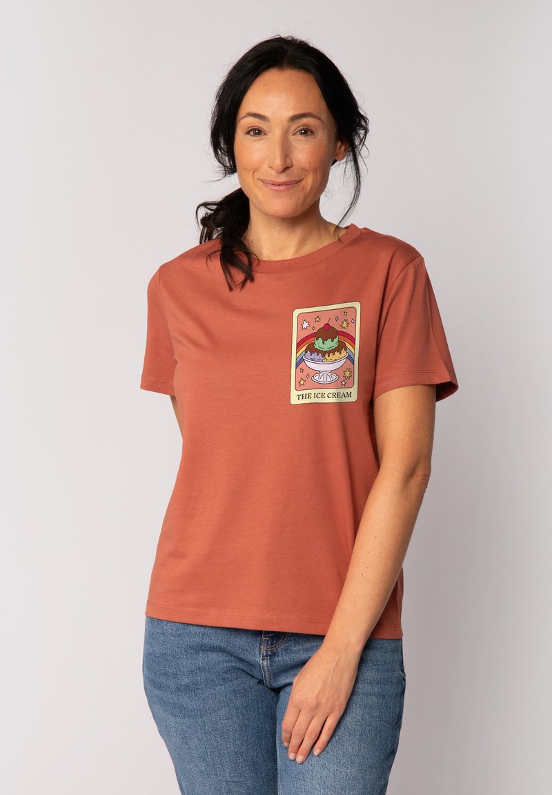 Rostfarbenes T-Shirt mit kurzen Ärmeln aus Baumwolle, das ein buntes Eiscreme-Motiv mit Sternen auf der Vorderseite zeigt. Lockerer Schnitt und Rundhalsausschnitt.