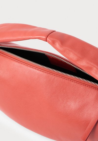 Τσάντα ώμου από μαλακό κοραλλένιο δέρμα με φαρδιά επενδεδυμένη λαβή και μερικώς ανοιχτό ασημένιο φερμουάρ που αποκαλύπτει μαύρη εσωτερική επένδυση.