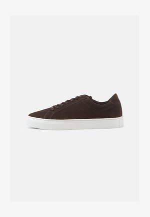 Sneaker in suede marrone con suola in gomma bianca. Punta arrotondata, design con laccio piatto, cuciture minime e colletto imbottito per il comfort.