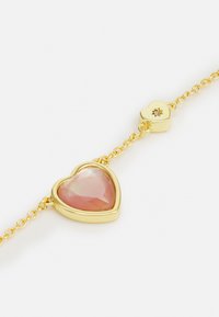 Bracelet chaîne en or avec un pendentif central en forme de cœur facetté en pierre précieuse rose et un petit charme en forme de cœur en or massif avec une découpe en forme d'étoile.
