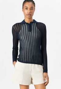 Navy longsleeve poloshirt met een gestructureerd, ribbelontwerp en een contrasterende kraag. Voorzien van een knopenlijst en een getailleerde pasvorm.