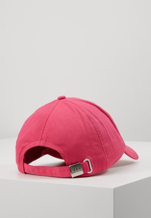 Lyserød justerbar baseballkasket med metal spænde bagpå, der viser "KARL" logo, hvilende på en hvid overflade mod en ensfarvet grå baggrund.