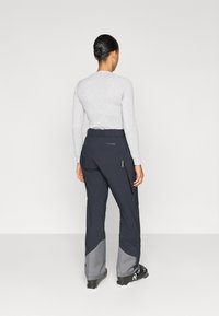 Σκι παντελόνια σε ναυτικό μπλε με γκρι αποχρώσεις, κατασκευασμένα από ανθεκτικό ύφασμα. Διαθέτουν τσέπη με φερμουάρ και ζώνη στη μέση. Απλός σχεδιασμός, αδιάβροχα.