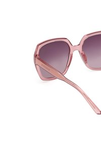 Gafas de sol rosas de gran tamaño con forma hexagonal, lentes degradados que van de oscuro a claro y montura de acrílico transparente.