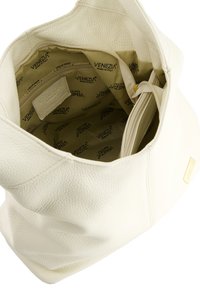 Biała torebka typu tote z fakturowanej skórki, o przestronnej interiorze z materiałową podszewką i wieloma przegrodami do organizacji.