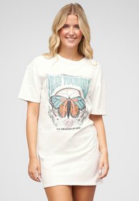 Kremowa sukienka t-shirt z grafiką niebieskich i pomarańczowych motyli z kwiatowymi akcentami oraz napisem "WYZWÓL SIĘ". Krótkie rękawy.
