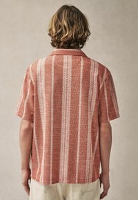 Kortærmet skjorte i et rustfarvet og hvidstribet mønster, med en afslappet krave og tekstureret stof. Bagudsigt, afslappet pasform.