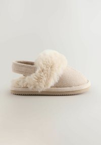Beige színű slip-on papucs, puha, bolyhos szőrme díszítéssel és nyitott hátsó pánttal, amely a benti kényelem és meleg érzet érdekében készült.