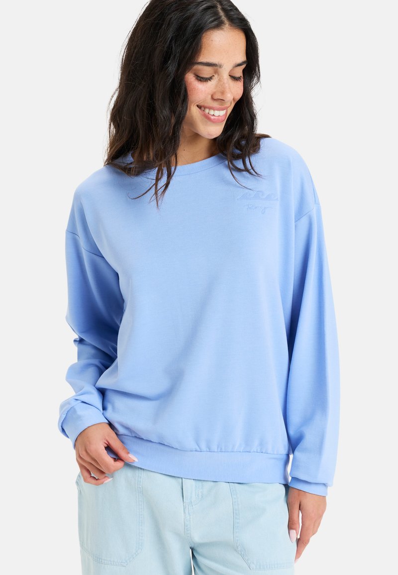 Sweatshirt bleu en matériau doux et léger, avec un col rond et des épaules tombantes. Équipé de poignets élastiques et d'un ourlet élastique.