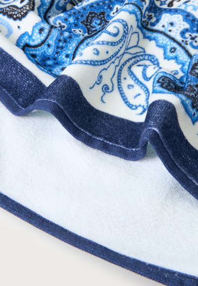 Tissu éponge doux avec des motifs cachemire bleus et noirs et des bordures bleu foncé unies, montrant la texture et des plis doux.
