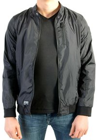 Sort bomberjakke lavet af glansfuldt materiale med ribstrikkede manchetter, lynlåslommer og en forlynlås uden krave. Bruges over en sort skjorte.