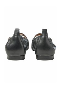 Scarpe basse in pelle nera con tacco basso, caratterizzate da un design cucito e accenti elastici sui lati per flessibilità e comfort.