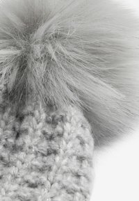 Šedá pletená čepice s velkým, nadýchaným šedým umělým koženým pom-pomem nahoře. Textura pleteniny je výrazná, s jemnými třpytivými vlákny.
