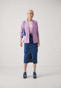 Laventeli puku takki vaaleanpunaisen paidan päällä, yhdistettynä denim-mittapituiseen hameeseen, jossa on etuhelma ja siniset korkeat platfrom-kengät. Mukana myös pieni sininen käsilaukku.