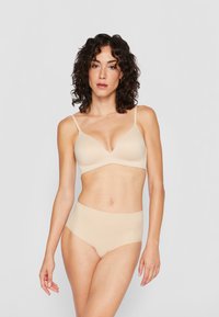 Soft, nude-colored bralette with a plunging neckline and adjustable straps, paired with matching high-waisted briefs in a smooth, seamless material.