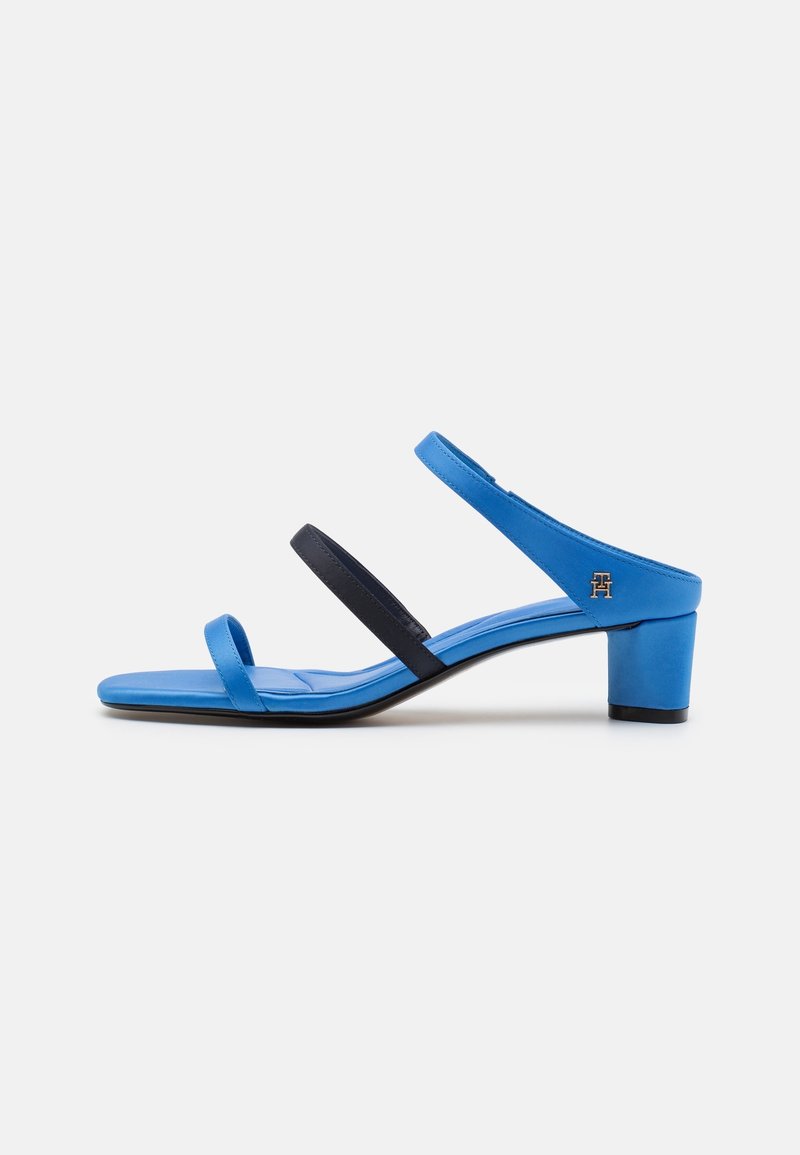 Sandale bleue à talon avec deux fines brides, une noire au milieu et une bleue autour de la cheville, avec un petit talon carré.