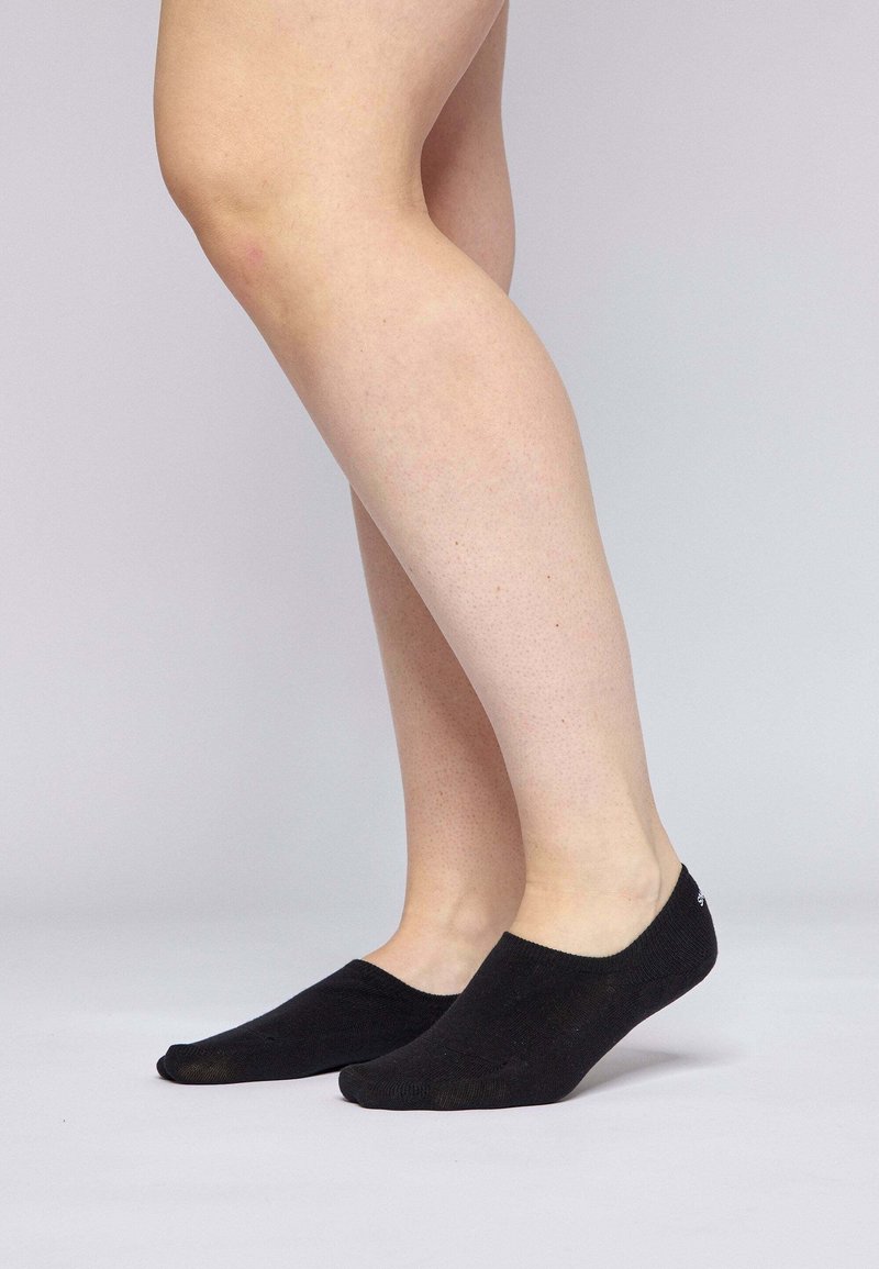 Black no-show socks made of soft fabric with a seamless design and light grip at the heel, featuring a subtle logo on the side.