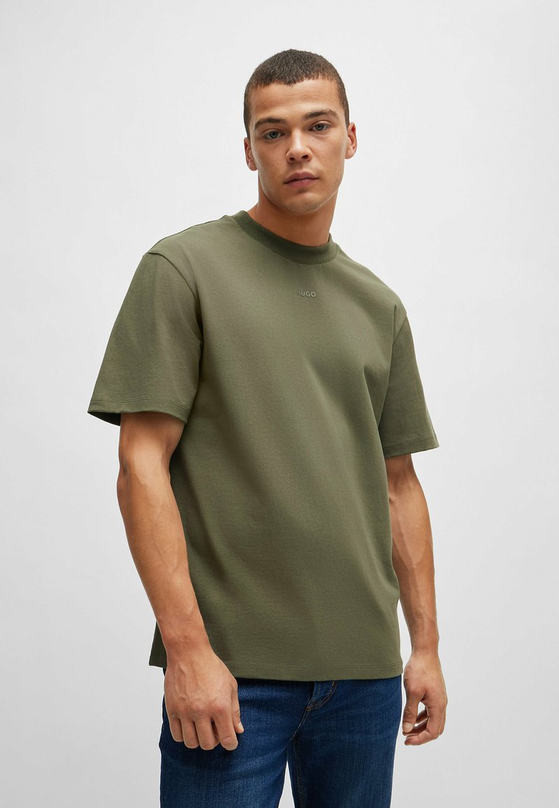 Olivgrön T-shirt med kort ärm i bomull. Har en rundad halsringning och minimal märkning framtill. Ledig passform.